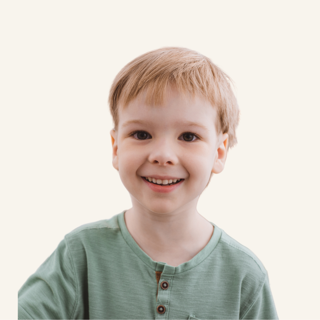 A young child with light brown hair and a green shirt smiles at the camera against a plain light background.